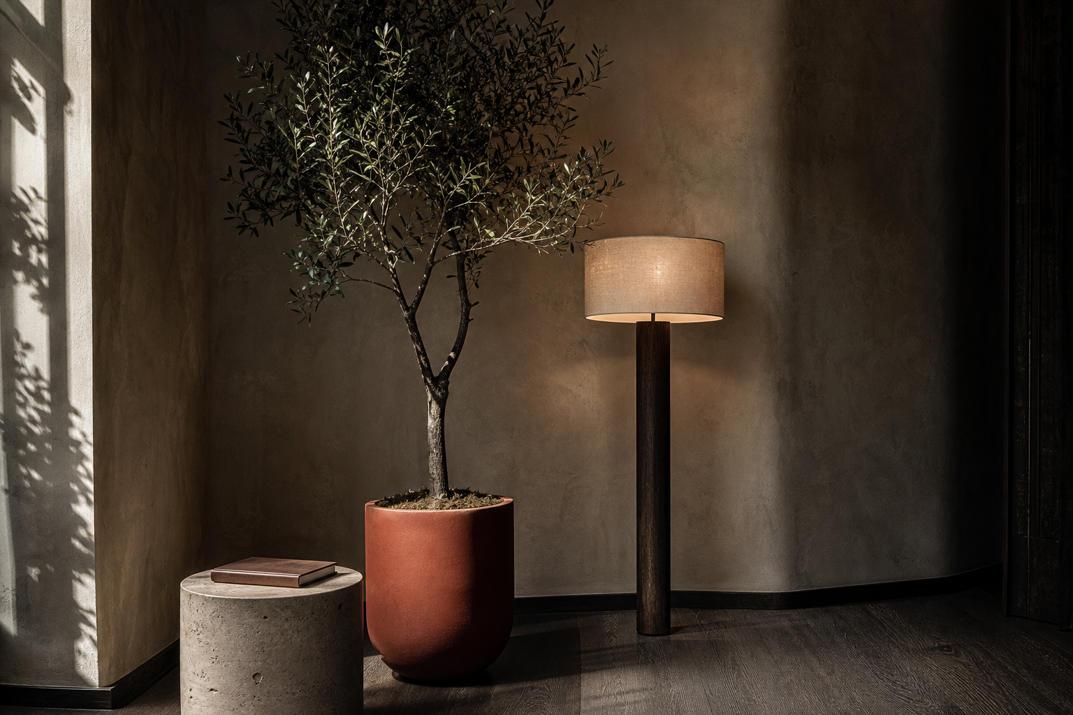 Living room corner styled with a tall faux olive tree, sculptural floor lamp and travertine stool against tadelakt walls