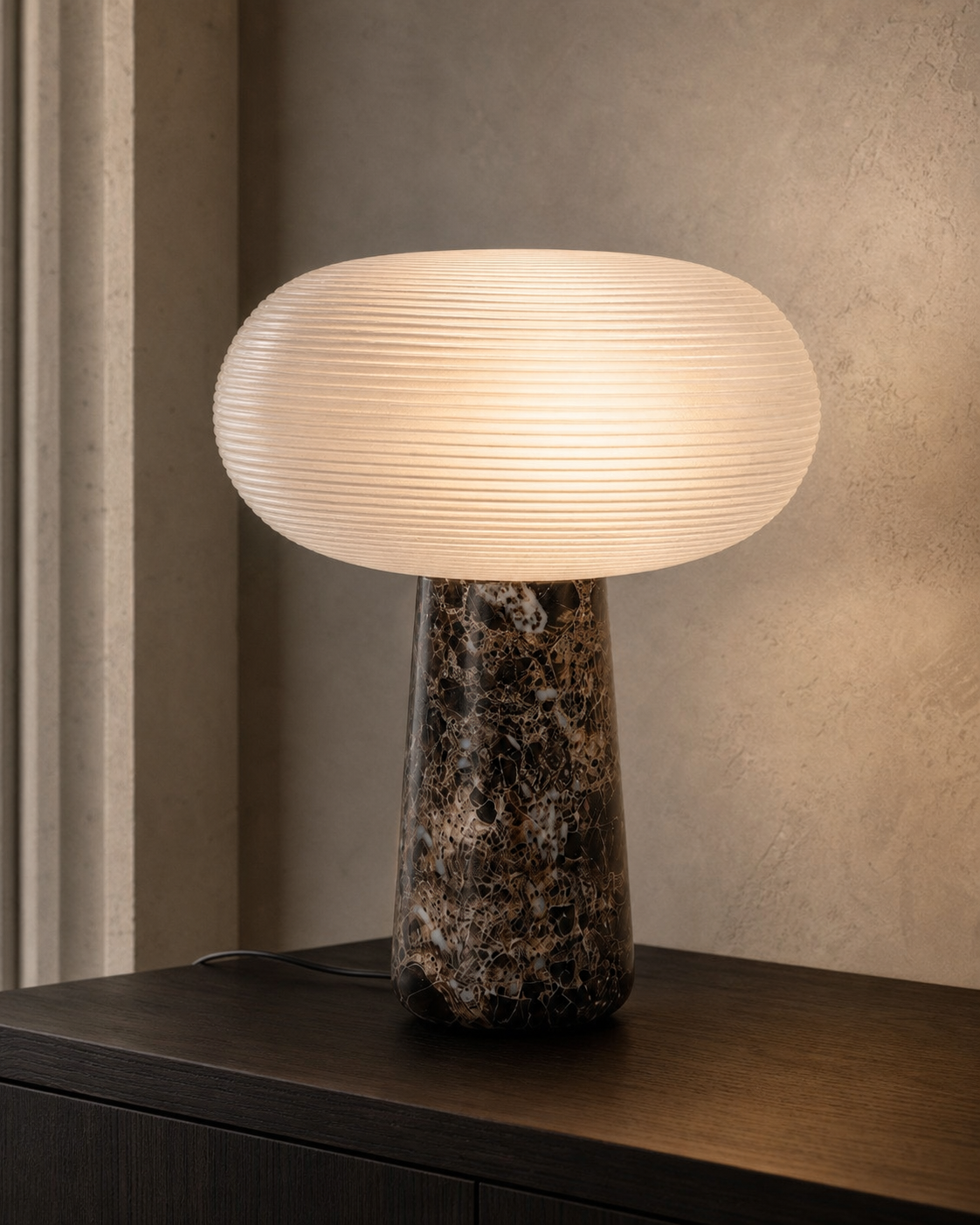 Lampe Brioche Maison Moya, verre nervuré et base en marbre, allumée sur un buffet sombre